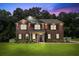 Beautiful brick two-story home with manicured lawn and inviting curb appeal at dusk at 1326 Harlequin Way, Stockbridge, GA 30281