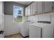 Well-lit laundry room with modern washer and dryer, storage cabinets and a view to the exterior at 1326 Harlequin Way, Stockbridge, GA 30281