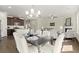 Open dining room area with a large table, white chairs, hardwood flooring, and adjacent kitchen and living room at 2628 Wild Laurel Ct, Norcross, GA 30071