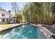 Inviting pool area surrounded by lush bamboo, a brick fence, and a stone deck with lounge seating at 4399 Jett Nw Pl, Atlanta, GA 30327