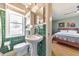 Green bathroom with a pedestal sink, toilet, and a view into the adjacent bedroom with hardwood floors at 1446 Lively Ridge Ne Rd, Atlanta, GA 30329