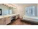 Bathroom featuring a large mirror, double sink vanity and a tub next to a window at 9185 Brockham Way, Alpharetta, GA 30022