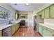 Well-lit kitchen featuring stainless appliances, wood floors, and light green cabinetry at 9185 Brockham Way, Alpharetta, GA 30022