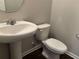 Stylish half-bathroom featuring a pedestal sink, white toilet, and modern fixtures at 11978 Lovejoy Crossing Way, Hampton, GA 30228