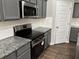 Close-up of a kitchen with stainless steel appliances, granite countertops, and white subway tile backsplash at 11978 Lovejoy Crossing Way, Hampton, GA 30228