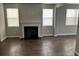 Cozy living room featuring a fireplace, wood flooring, and natural light from large windows with blinds at 11978 Lovejoy Crossing Way, Hampton, GA 30228