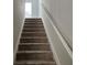 Carpeted staircase with a white handrail leading upstairs at 11978 Lovejoy Crossing Way, Hampton, GA 30228