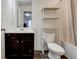 Well-lit bathroom with dark wood vanity, white countertop, toilet, and convenient shelving unit at 6356 Kennonbriar Ct, Lithonia, GA 30058