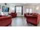 Bright living room featuring hardwood floors, a large window, and cozy red sofas and chairs at 6356 Kennonbriar Ct, Lithonia, GA 30058