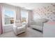 Charming Bedroom with floral wallpaper, featuring a glider, crib, and soft pink curtains for a serene setting at 3037 Ferrington Way, Smyrna, GA 30080