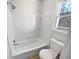 All-white bathroom featuring tiled walls, a bathtub, a toilet, and a window at 2925 Chesterfield Se Way, Conyers, GA 30013