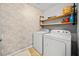 Functional laundry room featuring a washer, dryer, storage shelves, and stylish brick wallpaper at 113 Plumeria St, Canton, GA 30114
