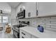 Kitchen showcasing white counters and cabinets, stainless steel appliances, subway tile backsplash, and view into the living area at 2767 3Rd Sw Ave, Atlanta, GA 30315