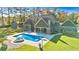 A backyard view of a beautiful home with a pool and hot tub surrounded by a lush green lawn at 650 New Morn Dr, Hampton, GA 30228