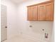 Bright laundry room featuring wooden cabinets with gold handles and tile flooring at 6490 Mockingbird Rd, Cumming, GA 30028