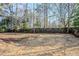 Fenced backyard showcasing a large, mostly dry grass area surrounded by mature trees and shrubs at 5438 Zachary Dr, Stone Mountain, GA 30083