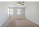 Bright bedroom with neutral paint, two windows, a ceiling fan and tan carpet at 5438 Zachary Dr, Stone Mountain, GA 30083