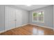 Bright bedroom features hardwood floors, neutral paint, a double-door closet, and a window at 1551 Avon Ave, Atlanta, GA 30311