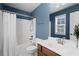 Bright bathroom featuring a shower-tub combo, white tile, and a vanity with a wood cabinet and white countertop at 3760 Lake Point Blvd, Suwanee, GA 30024