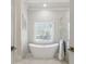 Elegant bathroom with a freestanding tub, marble accents, and a large window at 4434 Oglethorpe Nw Loop, Acworth, GA 30101
