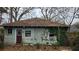 Shows the exterior of a rundown house, featuring weathered siding and overgrown vegetation at 1687 Neely Ave, Atlanta, GA 30344