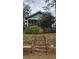 Shows a rundown house's front exterior with brick foundation and overgrown yard, stairs and porch at 1687 Neely Ave, Atlanta, GA 30344