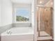A luxurious bathtub and shower combo, with a window offering natural light and a scenic view at 2023 Wyndham Pl, Conyers, GA 30013