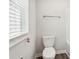 Bathroom with white toilet, window with blinds, and a chrome towel rack at 2023 Wyndham Pl, Conyers, GA 30013