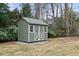 Exterior view of a backyard shed with light green siding, shingled roof, and white trim at 181 Pinehurst Ln, Marietta, GA 30068