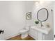 Modern powder room with a pedestal sink, round mirror, and hardwood floors at 1836 Memorial Dr # 303, Atlanta, GA 30317