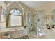 Bright bathroom with tiled glass shower, large tub, vanity with sink, and an arched window at 1301 Dayspring Trce, Lawrenceville, GA 30045