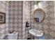 Stylish half-bathroom with unique patterned wallpaper and decorative oval mirror at 1301 Dayspring Trce, Lawrenceville, GA 30045