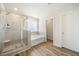 Modern bathroom boasts a glass-enclosed shower, a soaking tub, and wood-look floors for a spa-like experience at 1761 Dosk Ave, Lawrenceville, GA 30044