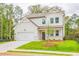Beautifully designed two-story home with white siding, lush lawn, and a two-car garage at 142 Henley St, Canton, GA 30114