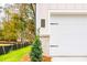 Attached white garage door with decorative hardware, set against a backdrop of green lawn and colorful trees at 142 Henley St, Canton, GA 30114