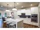 Modern white kitchen with stainless steel appliances, an island with seating, and stylish pendant lights at 264 Rockledge Sw Bnd, Powder Springs, GA 30127
