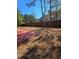 A yard with pine needles and a partially visible red concrete patio and tall fence in the background at 2622 Glenbrook, Loganville, GA 30012