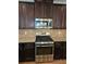 Stainless steel range and microwave surrounded by dark wood cabinets and granite countertops at 2622 Glenbrook, Loganville, GA 30012