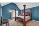 Bedroom with blue walls featuring a bed with dark wood pillars and natural light streaming in at 4869 Locherby Dr, Fairburn, GA 30213