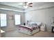 Well-lit primary bedroom with carpeted floor, tray ceiling, ceiling fan, and decorative wall art at 2268 Redfern Rd, Dacula, GA 30019