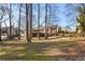 Expansive backyard with mature trees and a view of the home's back exterior, showing a raised deck and walkout basement at 3540 Honeycomb Se Dr, Conyers, GA 30094