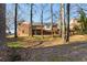 View of the brick home's backyard with a raised deck, set against a backdrop of mature trees and lush greenery at 3540 Honeycomb Se Dr, Conyers, GA 30094