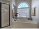 Luxurious bathroom featuring a soaking tub, glass-enclosed shower, and a large window at 5327 Saville Nw Dr, Acworth, GA 30101