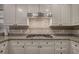 Close up of a kitchen featuring granite counters, tile backsplash, stainless vent hood and white cabinetry at 5327 Saville Nw Dr, Acworth, GA 30101