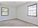 Cozy bedroom featuring neutral carpet, bright white walls, and natural light from two windows at 6035 Wintergreen Rd, Norcross, GA 30093