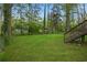 Spacious backyard featuring a large grassy area, mature trees, and a wooden deck, perfect for outdoor activities at 2132 Penrose Dr, East Point, GA 30344