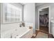 Inviting bathroom featuring a large soaking tub, tiled walls, and a walk-in closet at 509 Plantation Creek Dr, Loganville, GA 30052