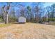 View of a white shed in the large backyard with mature trees in the background at 8176 Camp St, Douglasville, GA 30134