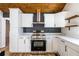 Modern kitchen with white cabinetry, stainless steel range hood, and gray accent wall at 8176 Camp St, Douglasville, GA 30134