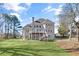 Expansive backyard featuring lush green lawn, mature trees, and a two-story home with a private back deck at 7015 Polo Dr, Cumming, GA 30040